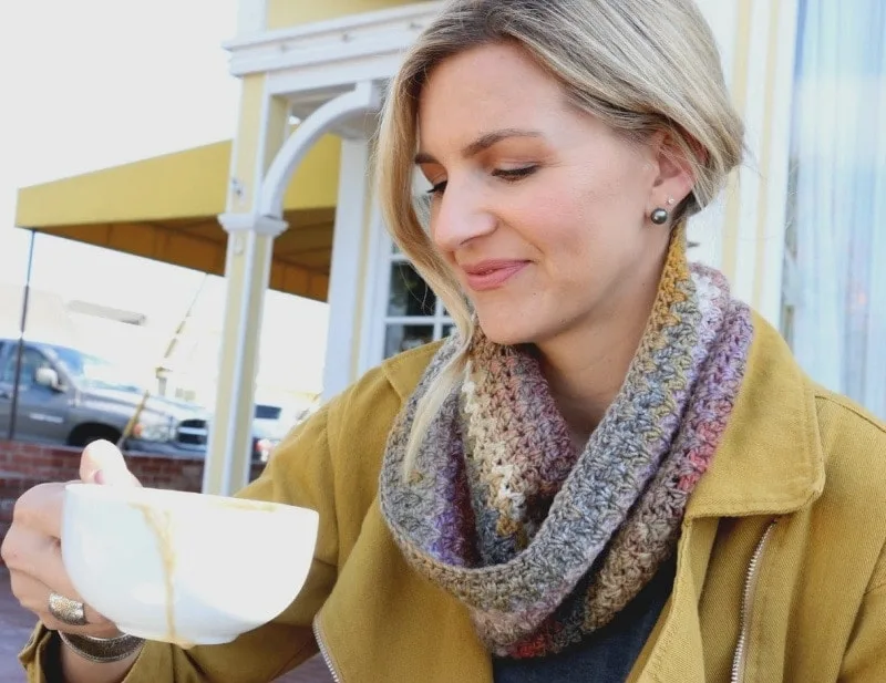Mel wearing small crochet scarf drinking coffee